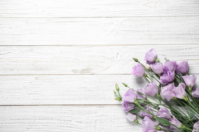 Photo of Beautiful fresh Eustoma flowers on white wooden table, flat lay. Space for text