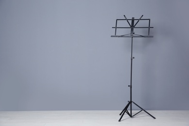Photo of Empty music note stand near grey wall indoors. Space for text
