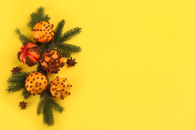 Photo of Flat lay composition with pomander balls made of fresh tangerines on yellow background. Space for text