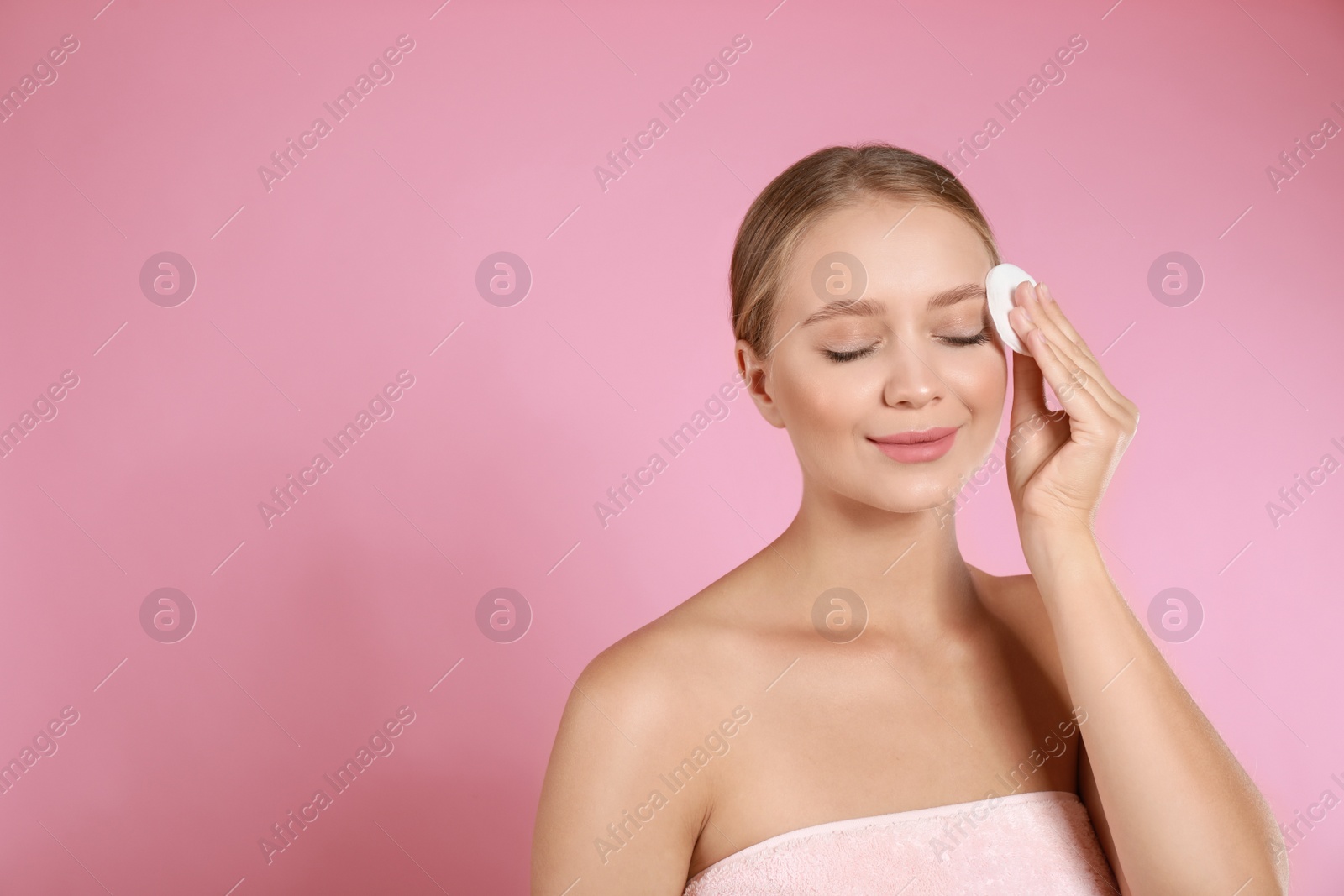 Photo of Beautiful young woman with cotton pad on pink background. Space for text