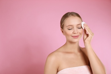 Beautiful young woman with cotton pad on pink background. Space for text