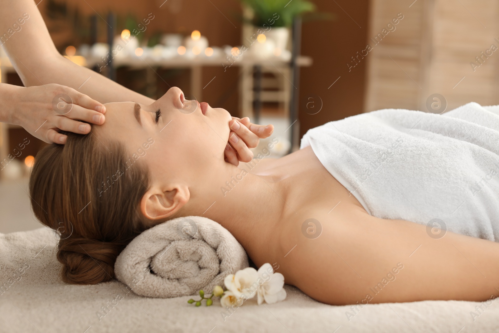 Photo of Young woman enjoying face massage in spa salon