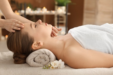 Photo of Young woman enjoying face massage in spa salon