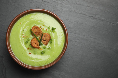 Photo of Tasty homemade zucchini cream soup on black table, top view. Space for text