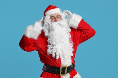 Photo of Merry Christmas. Santa Claus in headphones listening to music on light blue background