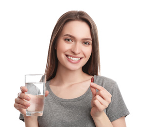 Young woman with vitamin pill and glass of water on white background