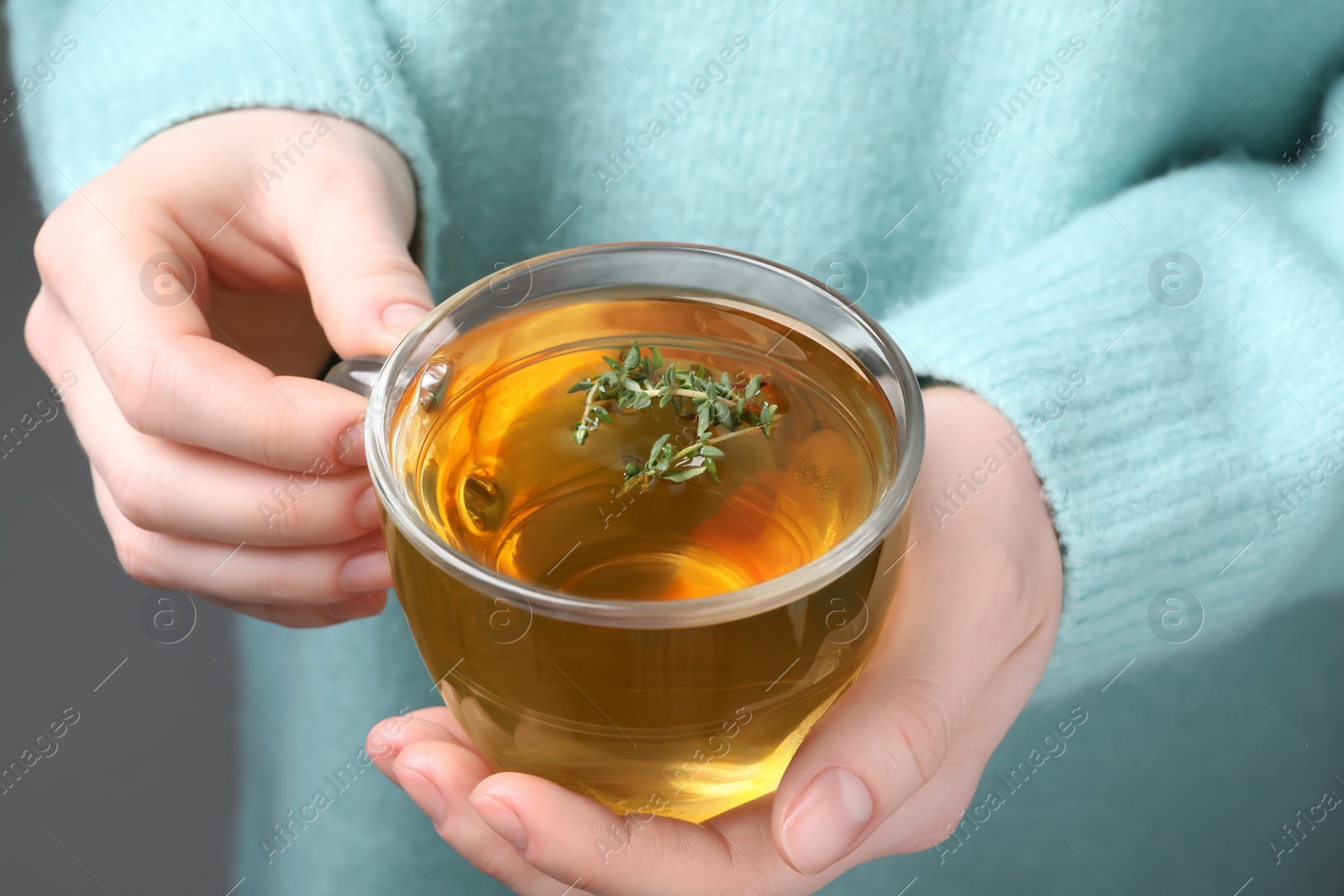 Photo of Woman holding cup of tasty herbal tea with thyme, closeup