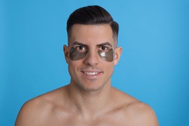 Photo of Man with dark under eye patches on light blue background