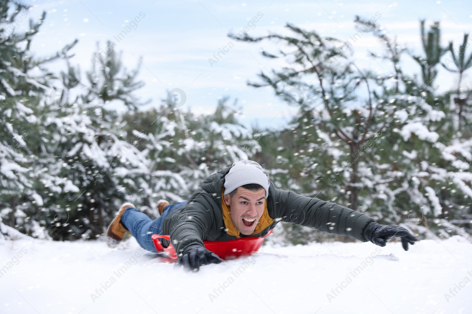 Photo of Happy man sledding outdoors on winter day. Christmas vacation