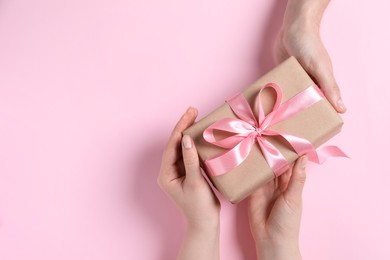 Photo of Man giving gift box to woman on pink background, top view. Space for text