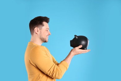 Man with piggy bank on color background