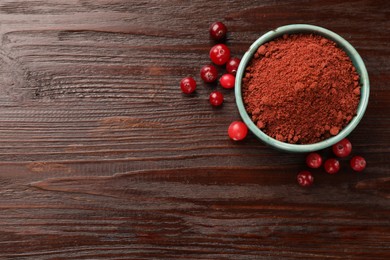 Photo of Dried cranberry powder in bowl and fresh berries on wooden table, top view. Space for text