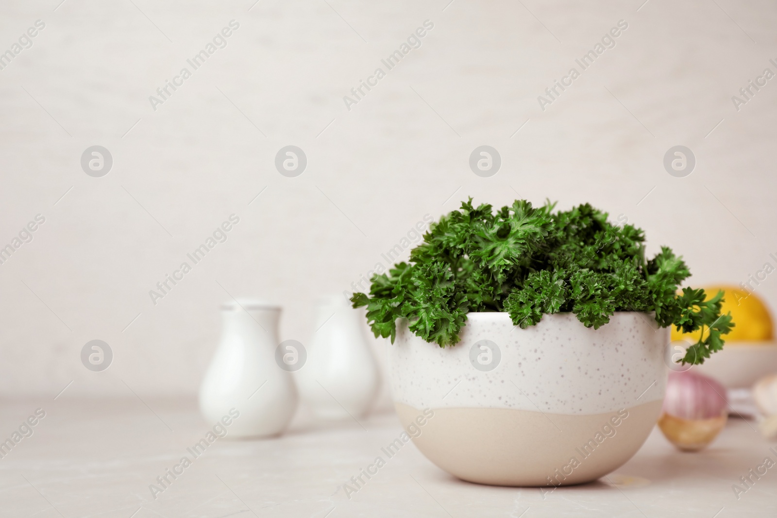 Photo of Bowl with fresh curly parsley on table