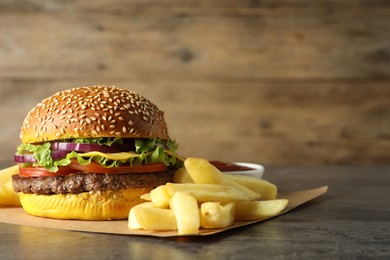 Photo of Burger with delicious patty and french fries on table, space for text