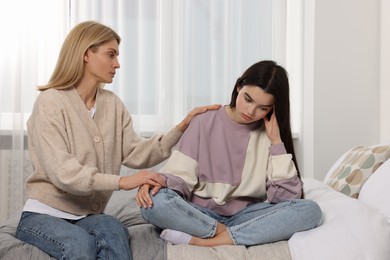 Photo of Mother consoling her upset daughter in bedroom. Teenager problems