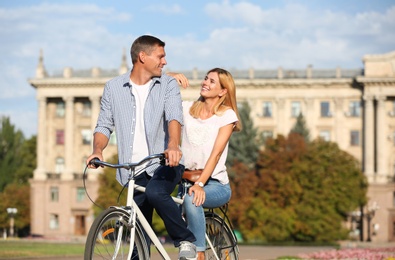 Photo of Happy couple riding bicycle outdoors on sunny day