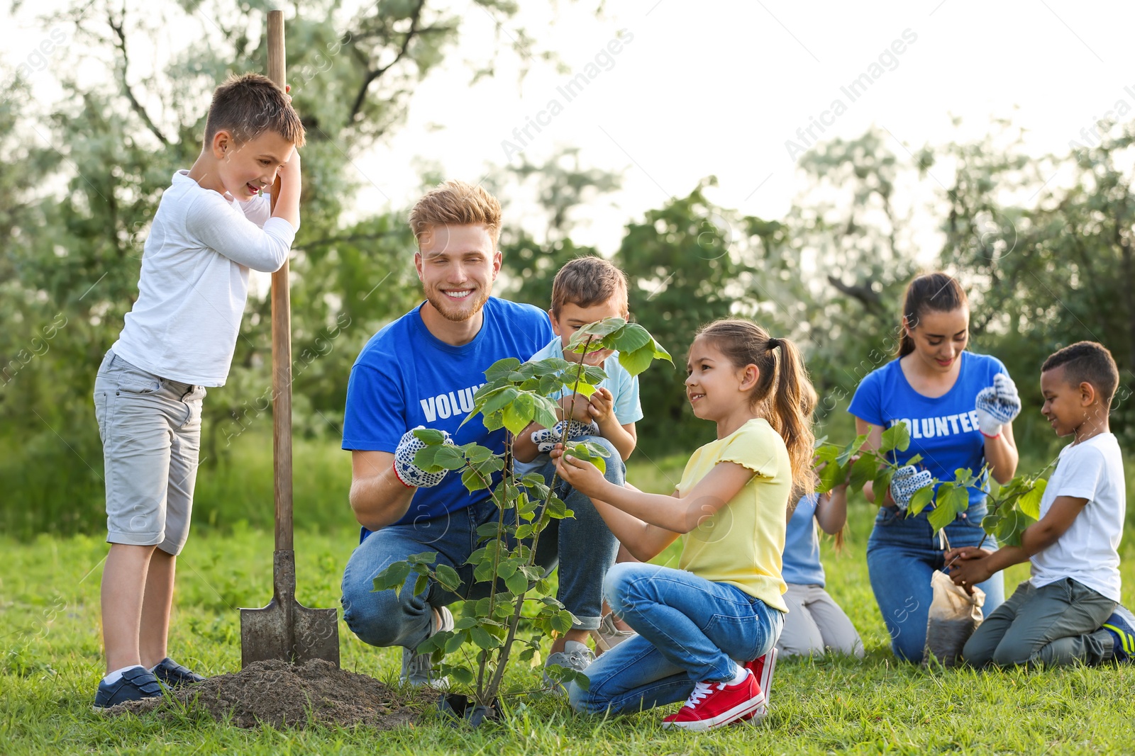 Photo of Kids planting trees with volunteers in park