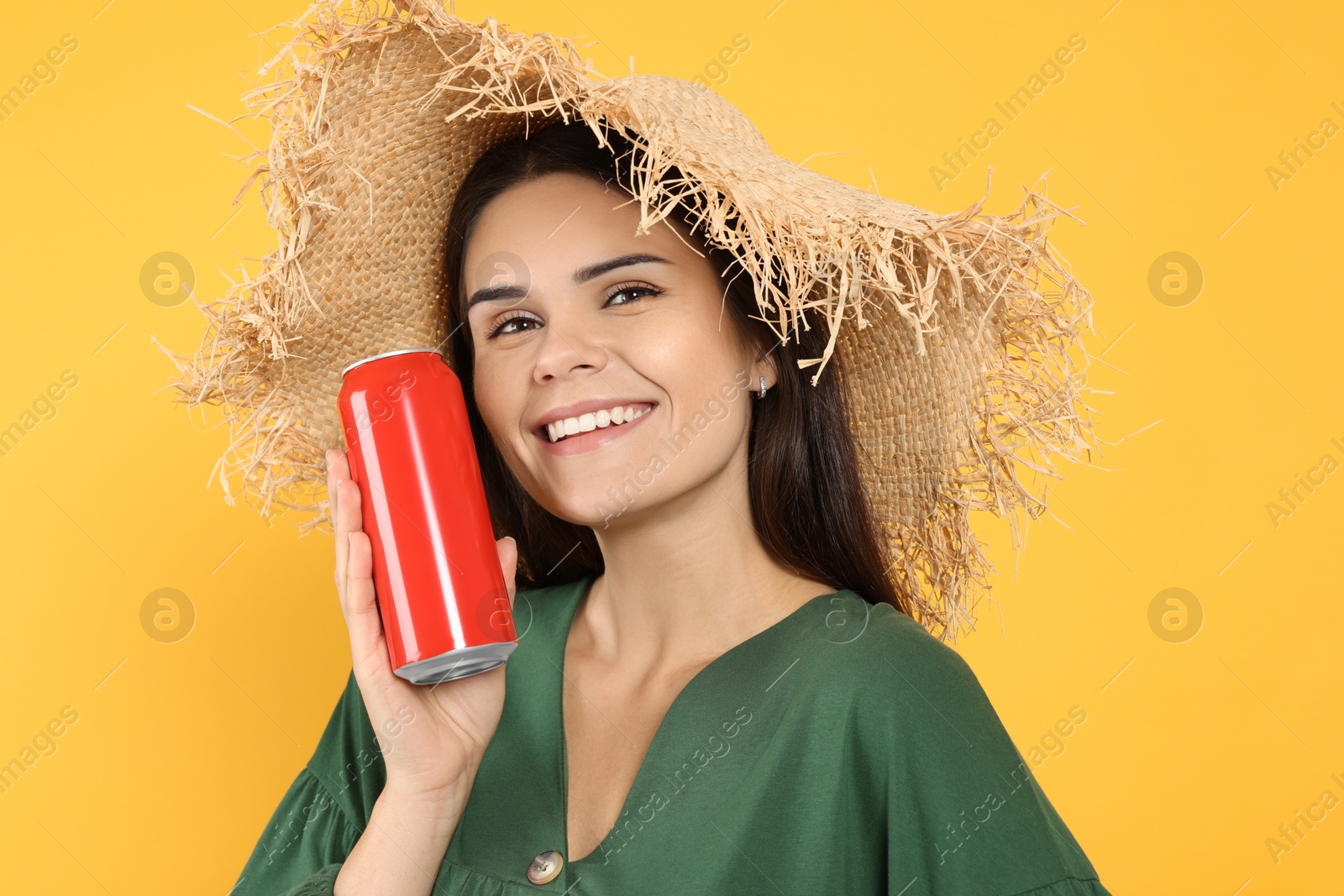 Photo of Beautiful happy woman holding red beverage can on yellow background