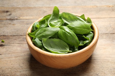 Photo of Fresh basil leaves in bowl on wooden table