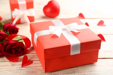 Beautiful gift box and roses on wooden table, closeup. Valentine's Day celebration