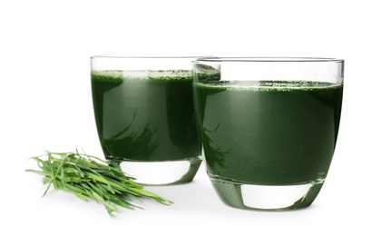 Photo of Glasses of spirulina drink and wheat grass on white background