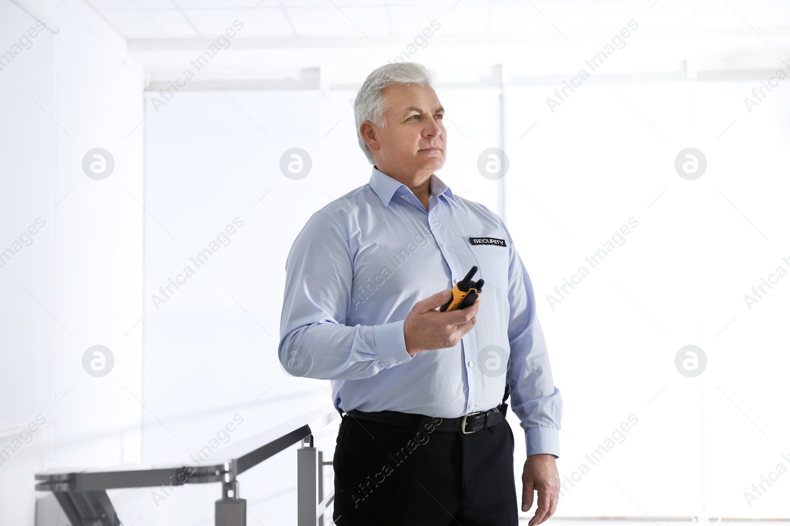 Photo of Professional security guard with portable radio set indoors