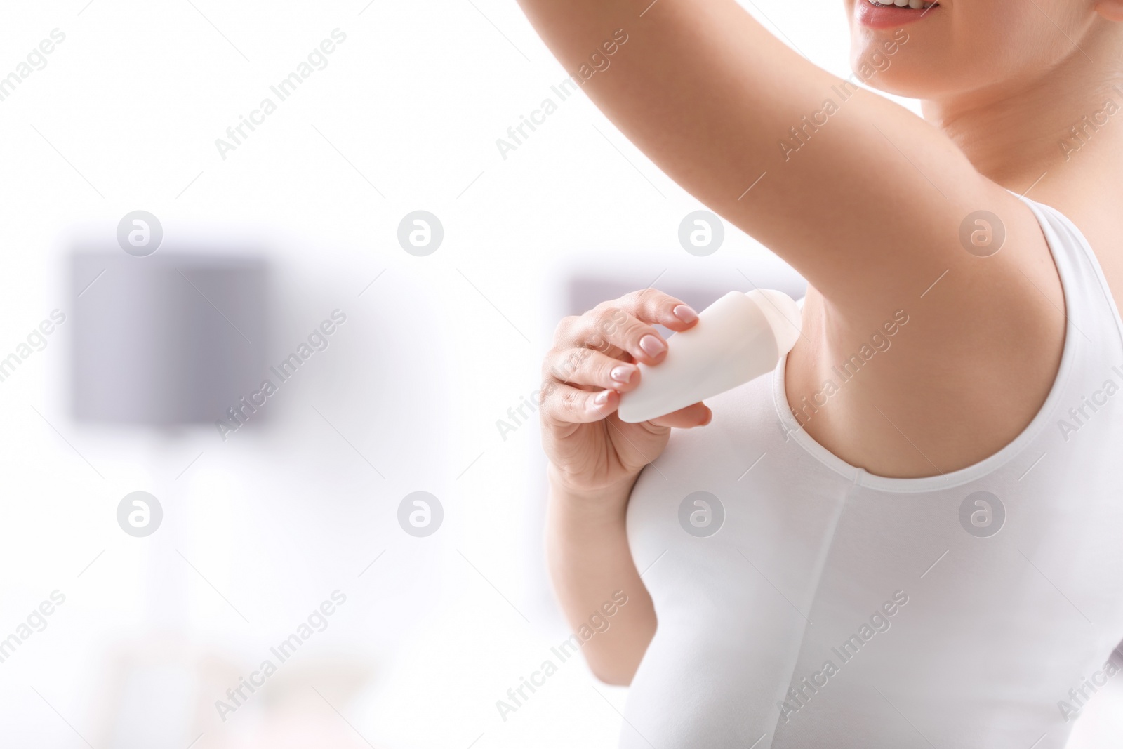 Photo of Beautiful young woman applying deodorant in bedroom. Space for text