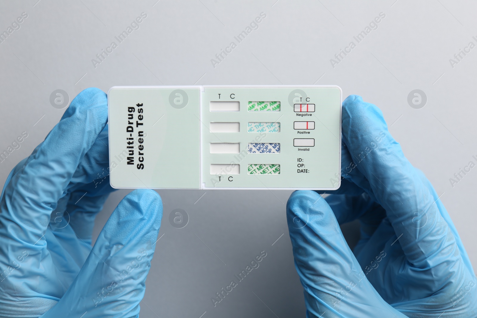 Photo of Doctor holding multi-drug screen test on light grey background, top view