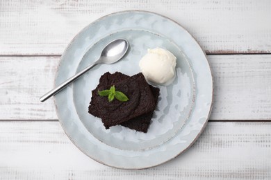 Photo of Tasty brownies served with ice cream and mint on white wooden table, top view