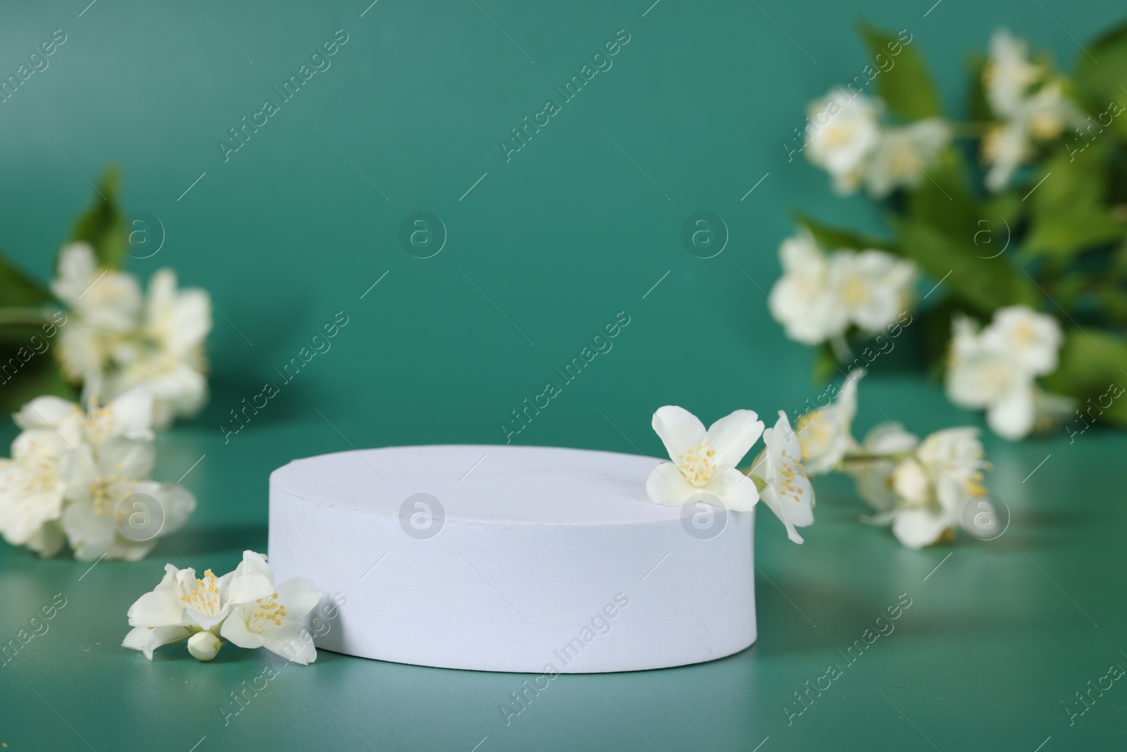 Photo of Presentation of product. White podium and beautiful jasmine flowers on green background