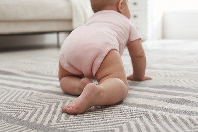 Cute baby crawling on floor at home, back view