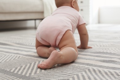 Photo of Cute baby crawling on floor at home, back view