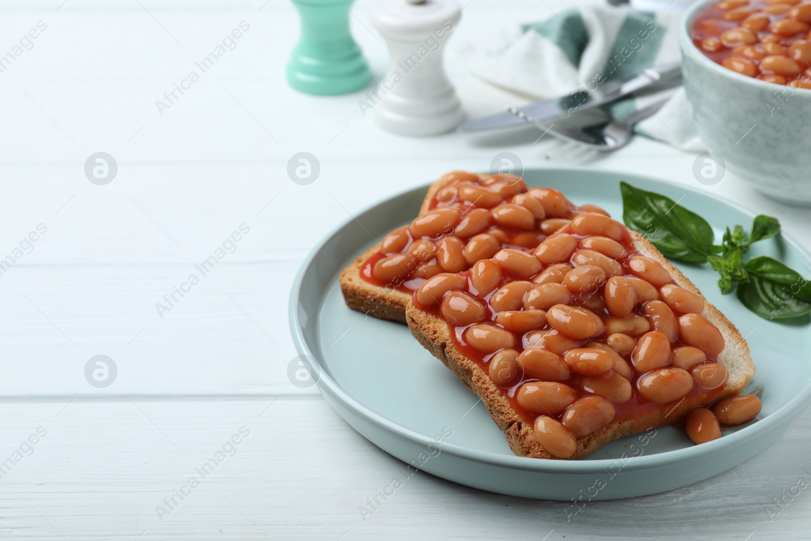 Photo of Toasts with delicious canned beans on white wooden table, space for text