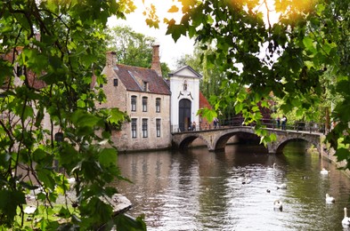 Photo of BRUGES, BELGIUM - JUNE 14, 2019: Bridge over canal and entrance gate to the Princely Beguinage Ten Wijngaerde