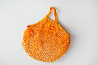 Photo of Empty orange net bag on white background, top view