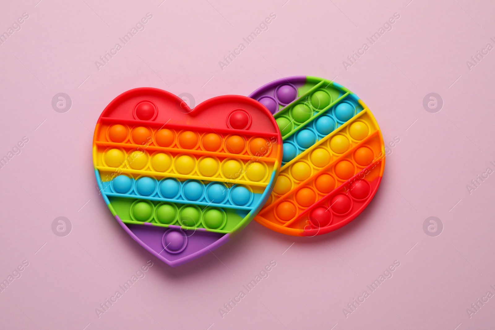 Photo of Rainbow pop it fidget toys on lilac background, flat lay