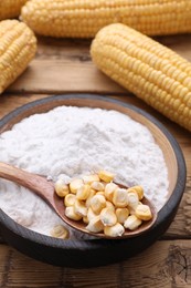 Photo of Bowl of corn starch and kernels on wooden table, closeup