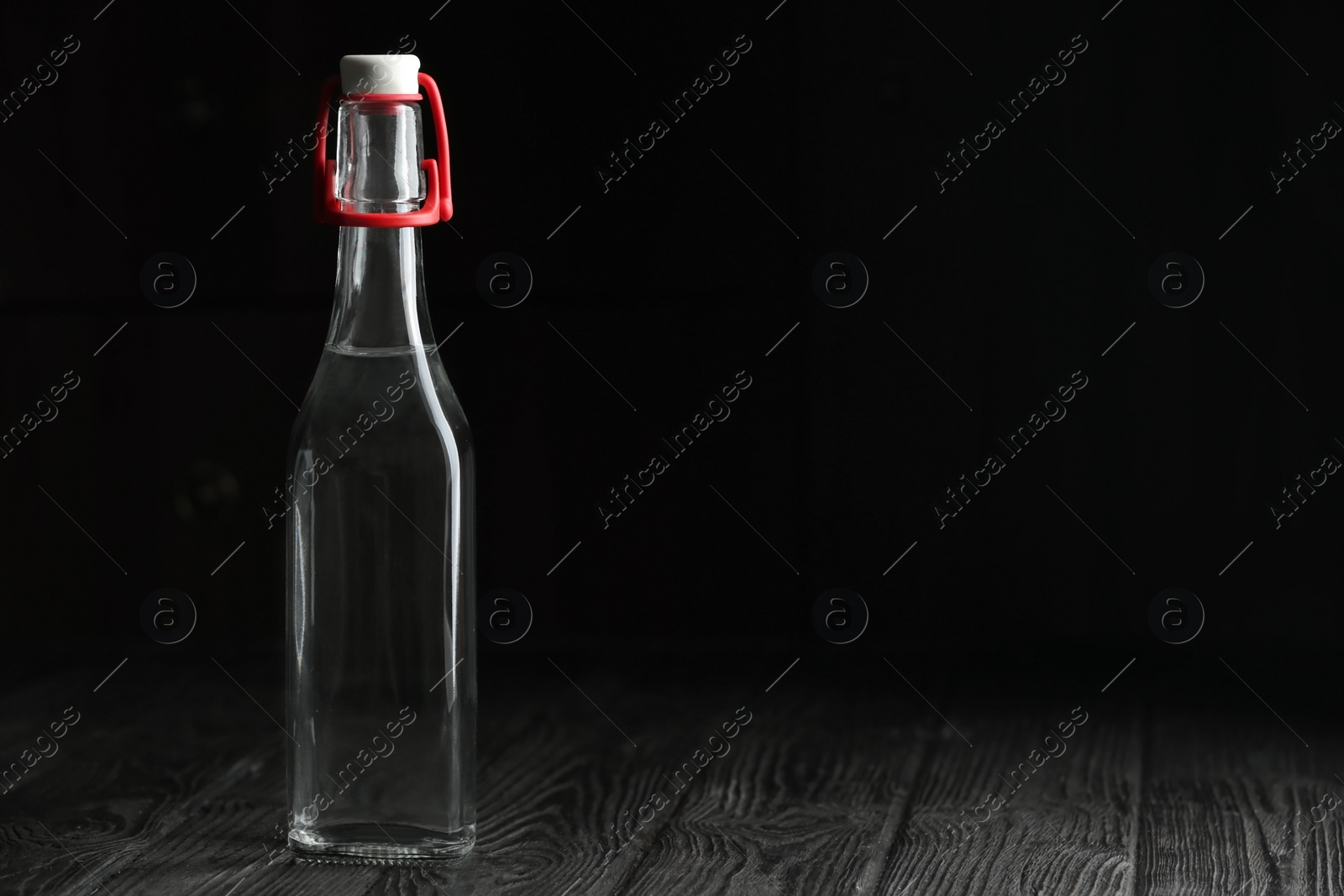 Photo of Glass bottle with vinegar and space for text on black background