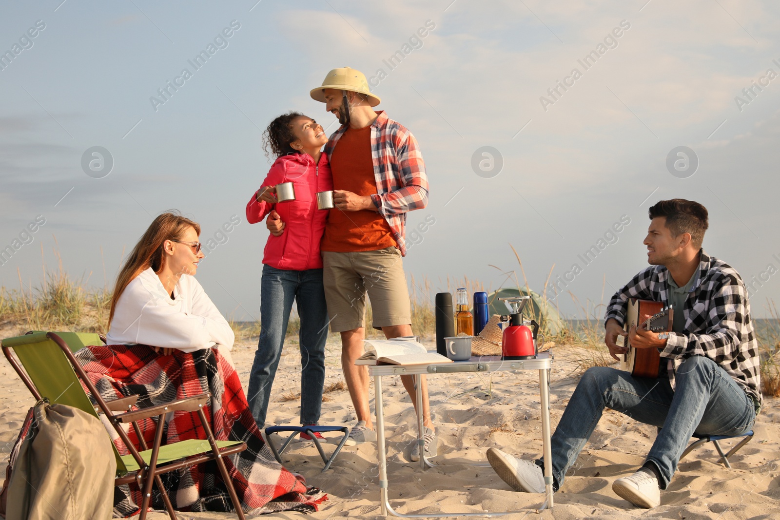 Photo of Friends resting on sandy coast. Beach camping