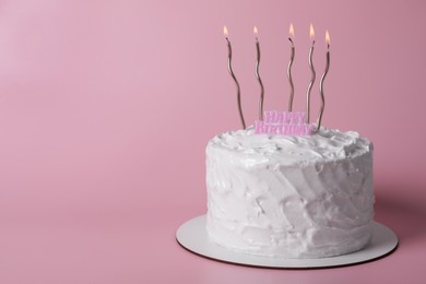 Delicious cake with cream and burning candles on pink background. Space for text