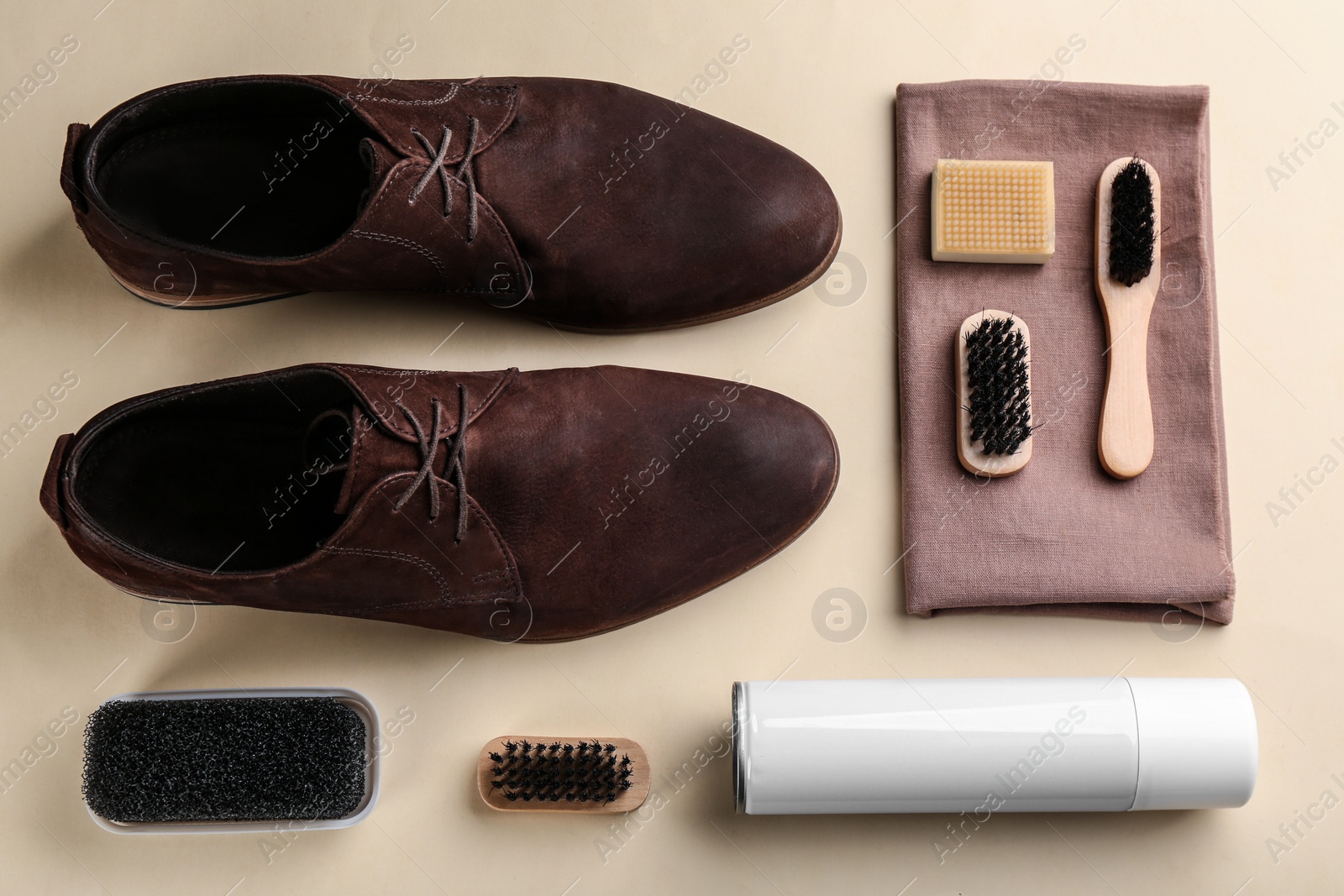 Photo of Stylish footwear with shoe care accessories on beige background, flat lay