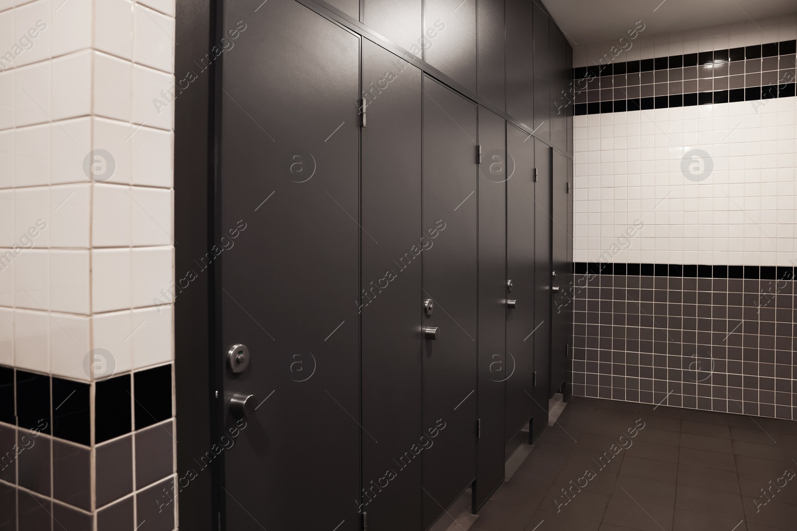 Photo of Public toilet interior with stalls and tiled walls