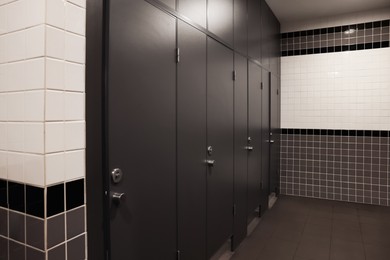 Photo of Public toilet interior with stalls and tiled walls