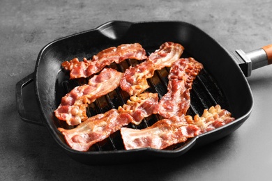 Grill pan with bacon on grey background