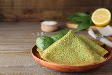 Photo of Delicious spinach crepes served on wooden table