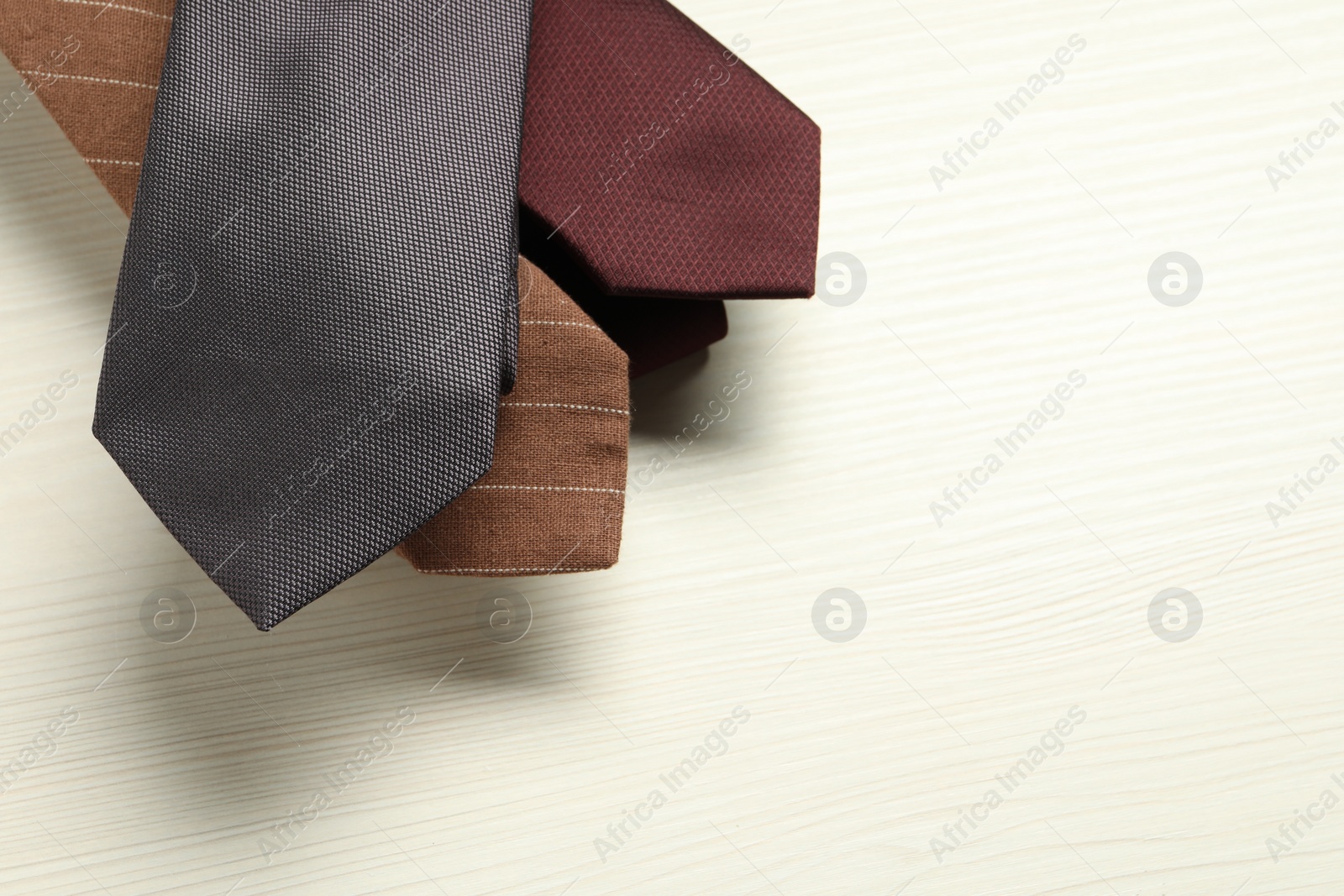 Photo of Different neckties on white wooden table, top view. Space for text