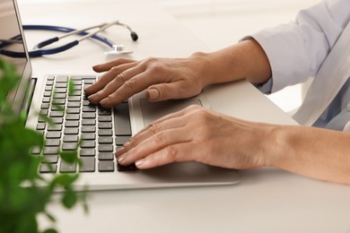 Photo of Doctor working on laptop at desk, closeup. Online medicine concept