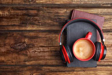 Books, coffee and headphones on wooden table, top view. Space for text