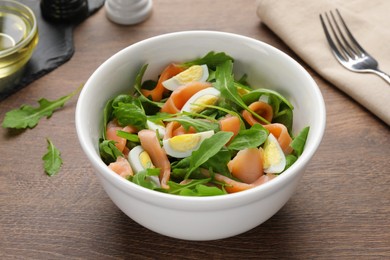 Delicious salad with boiled eggs, salmon and arugula on wooden table, closeup