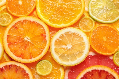 Slices of fresh citrus fruits as background, top view